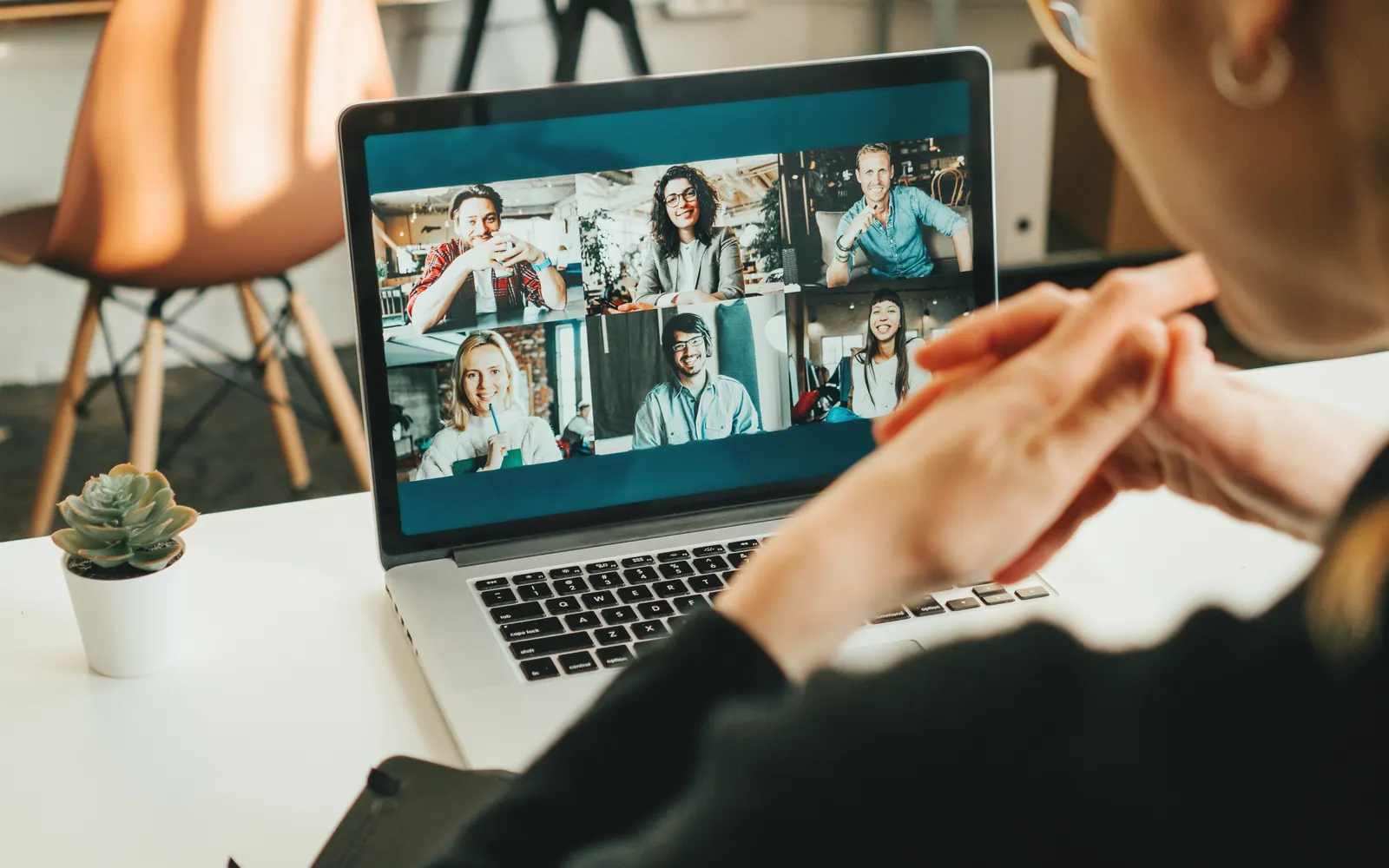 Laptop met een Teams-videogesprek, gezien over de schouder van een deelnemer aan tafel